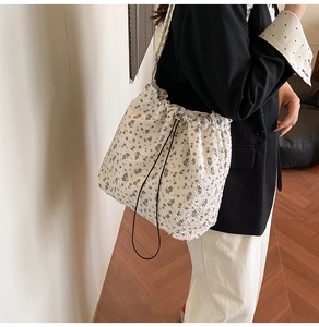 Detailed texture of the floral drawstring shoulder bag in a pleated cream fabric