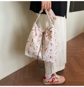 Close-up of white floral nylon bucket bag with red flower patterns and drawstring closure