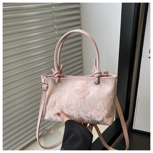 Detail of pink lace bucket bag with 3D butterfly embroidery and knotted handle
