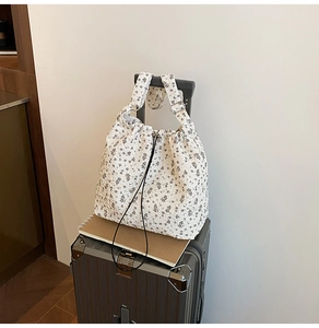 Detailed texture of floral nylon tote bag with drawstring closure on a suitcase