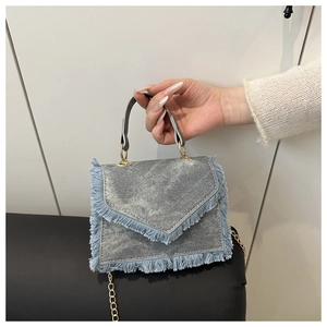Détail du sac à main en jean avec bords effilochés et bandoulière en chaîne dorée