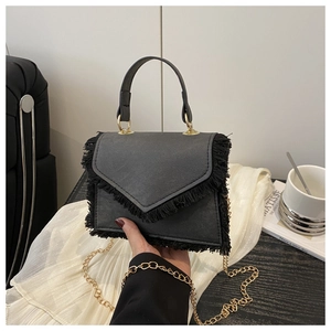 Détail du sac en similicuir noir avec bordure à franges et bandoulière dorée
