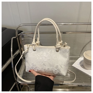 Close-up of white lace handbag with butterfly embroidery and round handles