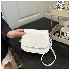 Close-up of a white leather saddle bag with Fashion Trend EST 1996 text being held