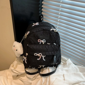 Black quilted backpack for women featuring colorful embroidered bows and a plush charm