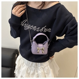 Detail showing a purple mini bow handbag with a silver chain strap worn by a model