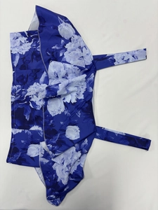 Detail eines blau-weißen Blumen-Oberteils mit Bindebändern und glänzender Oberfläche