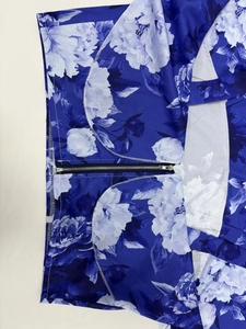 Detail des blauen Blumenkleides mit glatter Stoffstruktur und schwarzem Metallreißverschluss