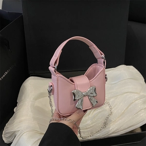 Pink mini handbag with silver metal bow and chain strap on satin background