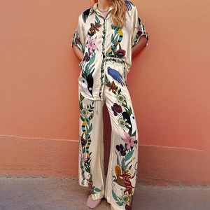 Detail of satin floral shirt and wide-leg trousers with vibrant bird and plant prints