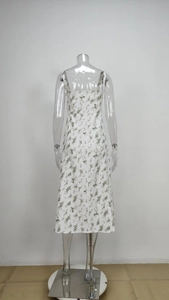 Detail of floral spaghetti strap maxi dress featuring green blossoms on white fabric