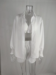 Dettaglio del set a tre pezzi bianco con camicia, top bikini e pantaloncini a vita alta