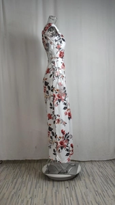 Vista laterale di un maxi abito bianco a fiori con rose rosse e design senza maniche