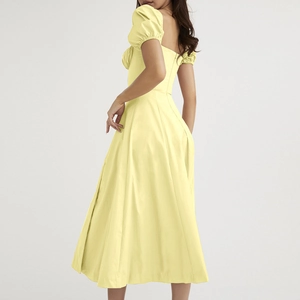 Detail view of French style pale yellow dress featuring puff sleeves and a sleek back zipper