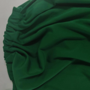 Close-up of dark green dress fabric featuring intricate pleating and draped texture
