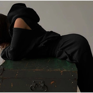 Detail view of the cold-shoulder cut on a black minimalist fleece hoodie and matching pants
