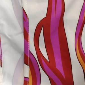Macro detail of silky fabric featuring abstract flame patterns and white stitching