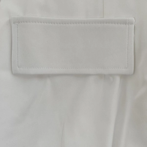 Close-up of elegant white long-sleeve dress showing detailed pocket stitching and fabric