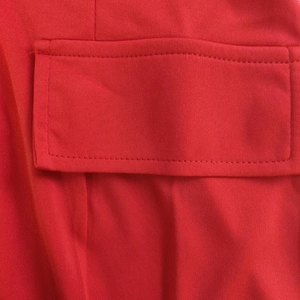 Detailed close-up of a red dress showing fabric texture and stitched pocket flap