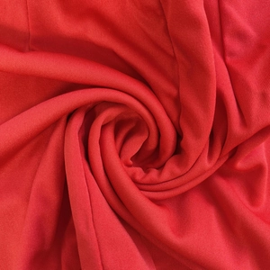 Macro view of the vibrant red knitted fabric texture with soft spiral folds
