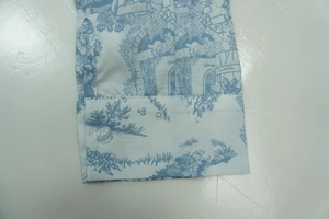 Detail shot of shirt cuff with blue Toile de Jouy scenic print and clear button