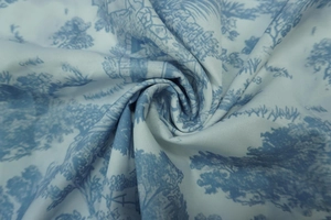 Detailed close-up of blue Toile de Jouy floral pattern on white cotton blend fabric