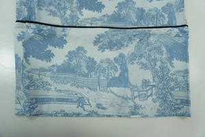 Close-up of blue Toile de Jouy print fabric with black piped edges on sleeve cuff