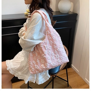 Detailed texture of pink floral lace tote bag styled with a white lace dress in a room