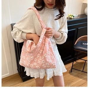 Close-up of pink tote bag with 3D white embroidered flowers and soft fabric texture
