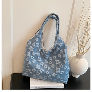 Detail of light blue tote bag featuring 3D embossed floral patterns and elegant texture
