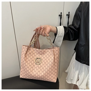 Detail of beige tote bag with M-pattern print, gold metal logo, and chain handle