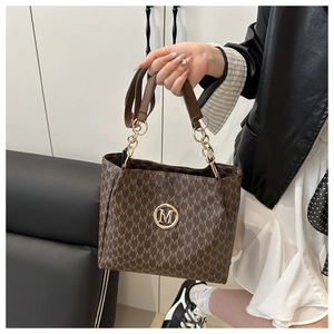 Detail of vintage monogram pattern and gold metal logo on a brown leather tote bag