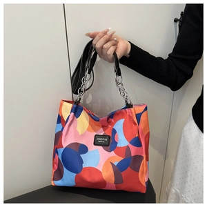 Detail of colorful geometric pattern tote bag with leather strap and chain accent
