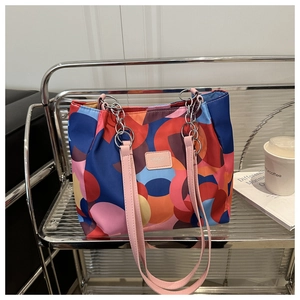 Detail of printed tote bag with pink leather strap and silver chain on metal rack