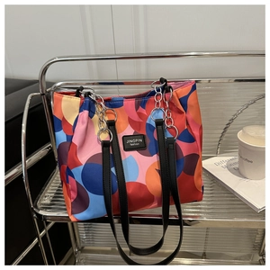 Detail of colorful geometric print tote bag with black strap and silver chain accent