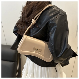 Beige faux leather crossbody bag featuring a golden bow buckle and knotted shoulder strap