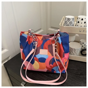 Close-up of colorful geometric print tote bag with pink leather handle and silver chain
