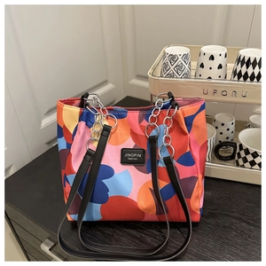 Detail of colorful geometric tote bag with black leather and silver chain strap