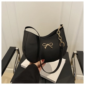 Close-up of black leather hobo bag with a gold bow buckle and decorative side chain