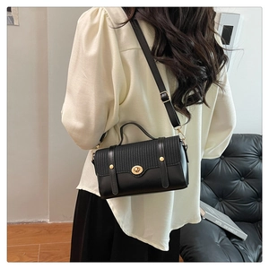 Detail van zwarte crossbodytas met geweven textuur en gouden sluiting op model