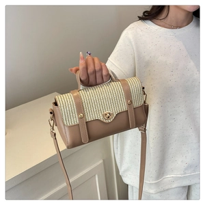 Detail van bruine lederen en geweven crossbodytas met gouden draaislot en klinknagels