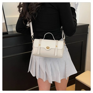 Detail of elegant beige square bag featuring a gold metal twist lock and textured flap