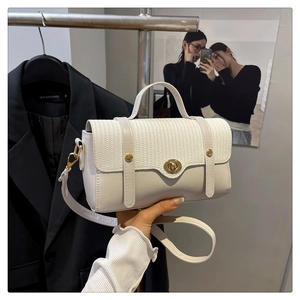 Detail van witte handtas met geweven flap, gouden draaisluiting en lederen schouderband