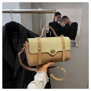Detail of woven straw and camel leather flap bag with a golden turn-lock closure