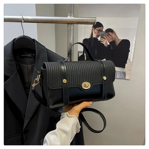 Detail of black woven texture flap and golden round turn-lock on the leather handbag