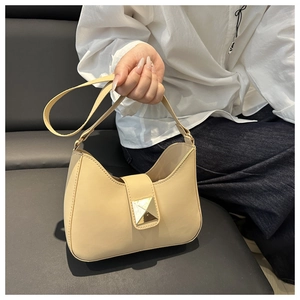 Détail du sac beige avec un fermoir métallique moderne en forme de pyramide dorée