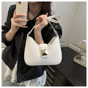 Détail du sac à bandoulière blanc avec boucle dorée sur une veste en cuir noir