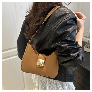 Gros plan du sac hobo en cuir marron avec boucle pyramidale dorée sur le mannequin