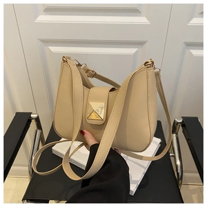 Détail du sac beige en simili cuir avec fermoir à clous dorés et poignée supérieure