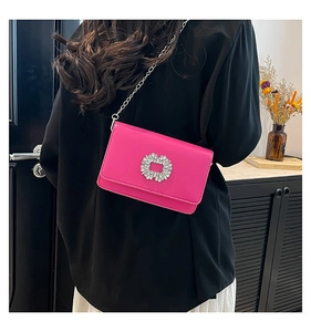Detail of rose pink leather crossbody bag with sparkling rhinestone buckle and silver chain